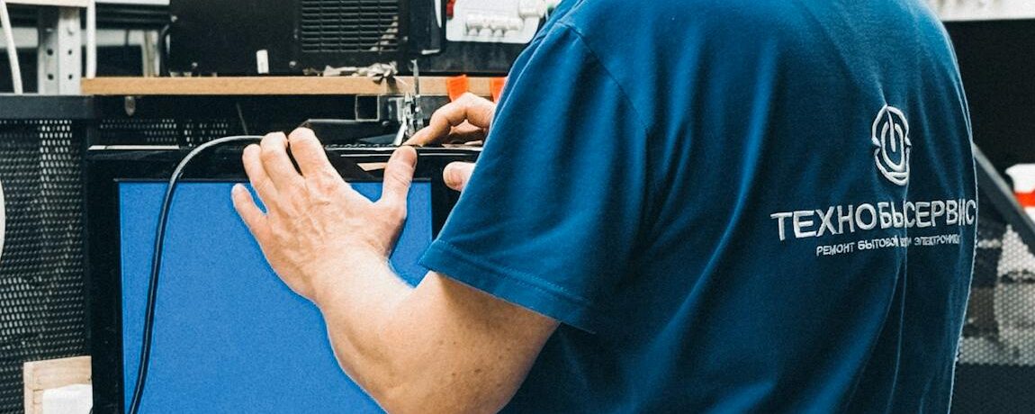 Adult male technician working on computer equipment in an electronics workshop.