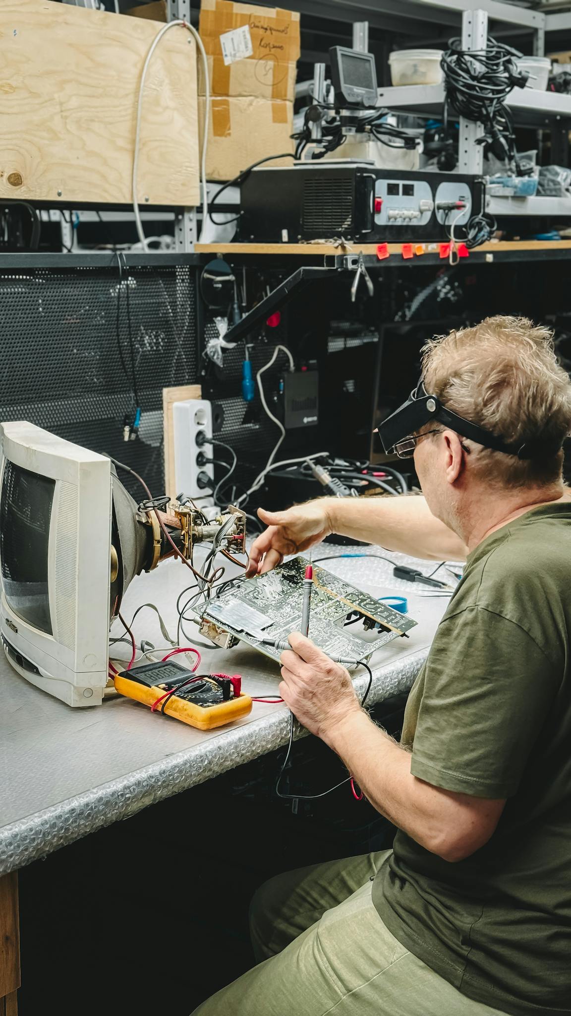 Technician working on electronic components in a workshop, focusing on circuit board repairs.